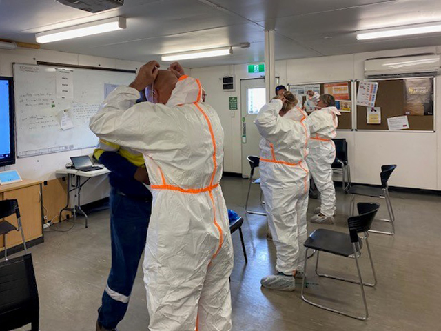 Sodexo employees taking training on donning coveralls 